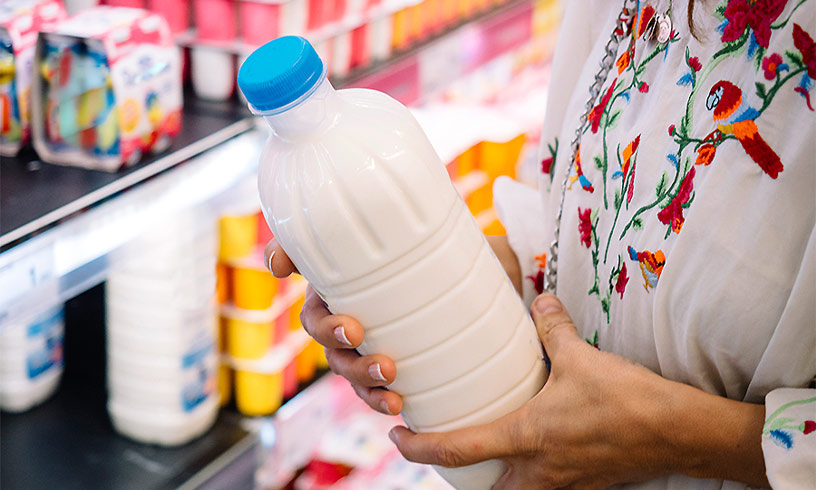 На зображенні руки людини, які тримають пляшку молока